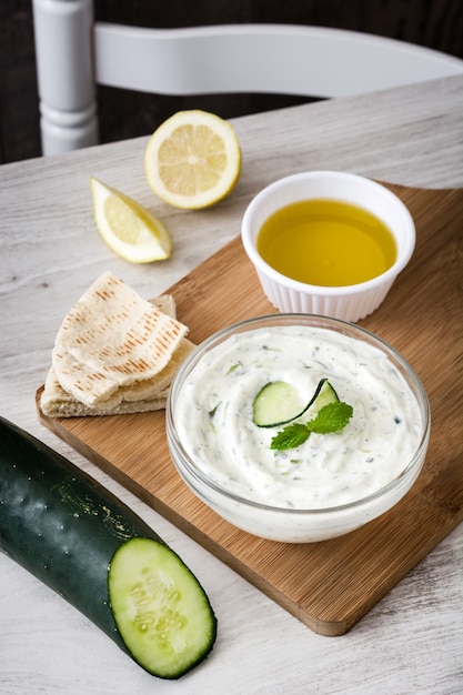 Tzatziki e ingredientes na mesa de madeira branca