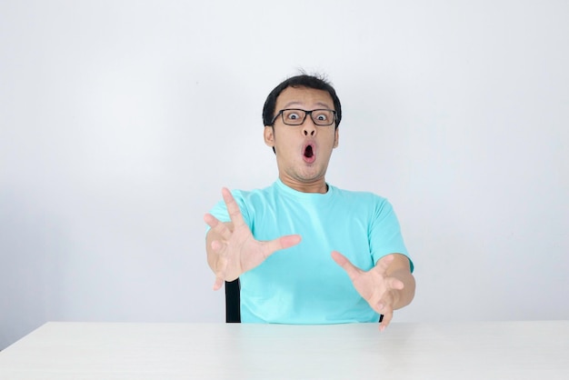 Uau e rosto chocado de um jovem asiático com gesto de mão aberta conceito de modelo de publicidade com camisa azul