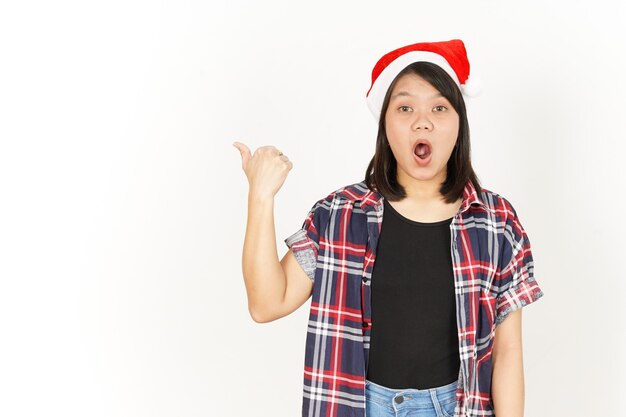 Uau e um produto apontador à esquerda de uma linda mulher asiática vestindo uma camisa xadrez vermelha e um chapéu de Papai Noel