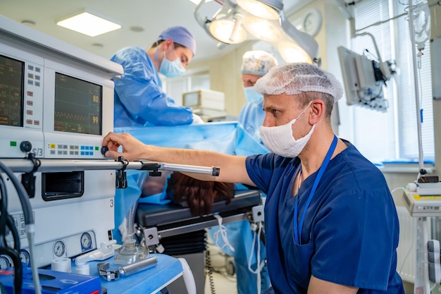 En la UCI. El médico cambia los parámetros de la ventilación pulmonar artificial en el quirófano moderno. De cerca.