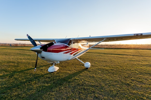 Foto ucrania kiev 11 de octubre de 2018: un pequeño avión de colores blanco y rojo de pie en el aeródromo sobre la hierba verde en el fondo del cielo.