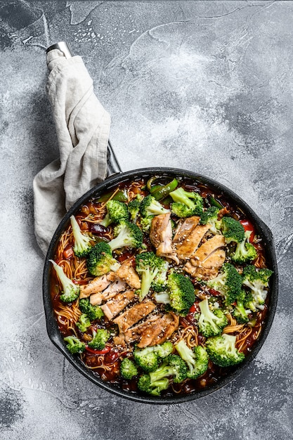 Udon brät Nudeln mit Huhn in einer Pfanne an. Ansicht von oben.