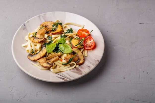 Udon mit Champignons und Spinat in einem Teller auf einer Betonoberfläche