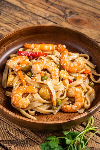 Udon refogado noodles com camarão camarão em uma tigela de madeira.