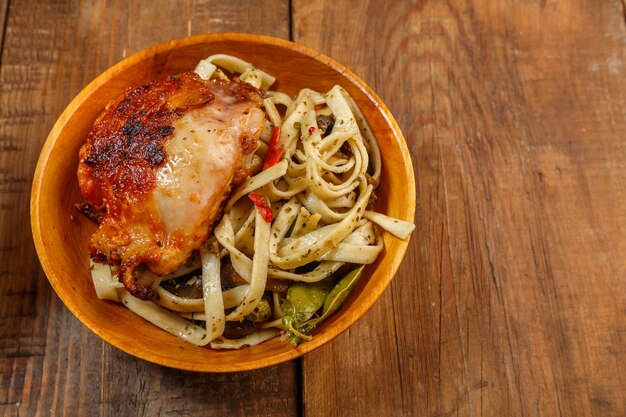 Udon con verduras y pollo con sésamo en un plato de madera sobre la mesa