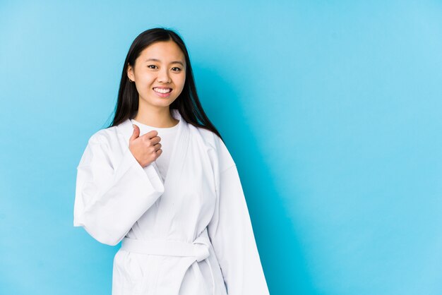 Übendes Karate der jungen chinesischen Frau lokalisierte Daumen oben lächeln und anheben