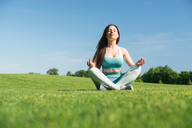 Übendes Yoga der athletischen Frau im Freien