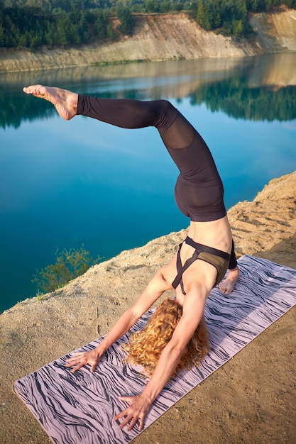 Foto Übendes yoga der attraktiven gelockten frau der rothaarigen draußen