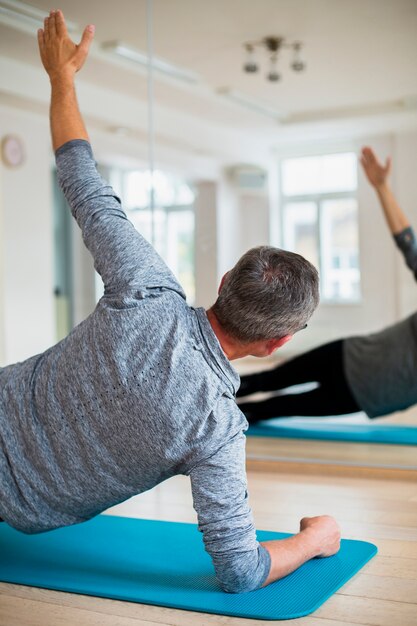 Foto Übendes yoga des älteren mannes der hinteren ansicht