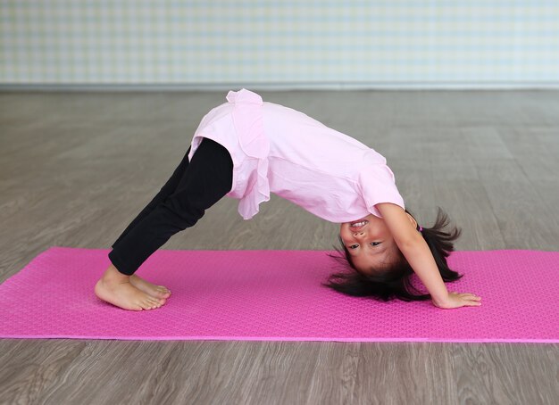 Übendes yoga des netten kleinkindmädchens und handeln der übung