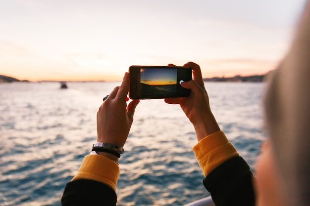 Foto Übergeben sie das halten des schwarzen smartphone, der ein foto von bosphorus-straße am sonnenunterganglicht macht