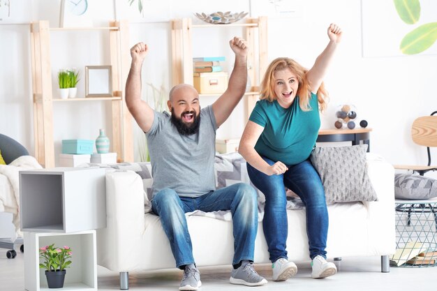 Foto Übergewichtige paare, die zu hause fernsehen