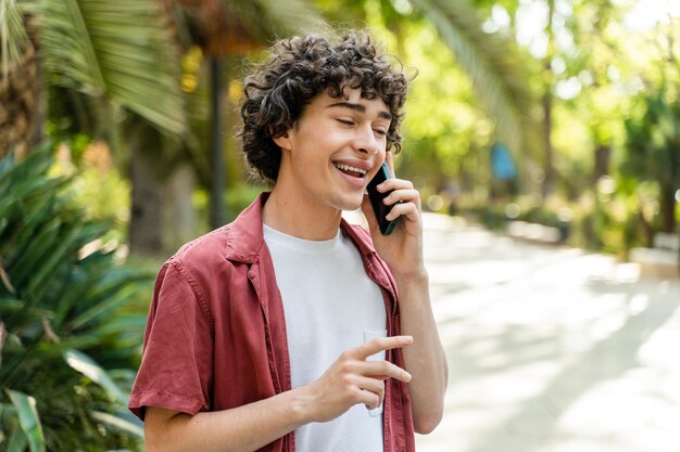 Überglücklicher Mann, der durch die Straße geht und mit jemandem per Smartphone chattet