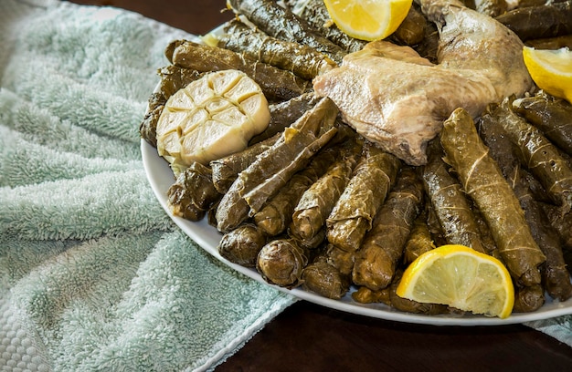 Überkopfaufnahme einer traditionellen arabischen Mahlzeit aus Weinblättern mit Hühnerfleisch, serviert mit Zitronen