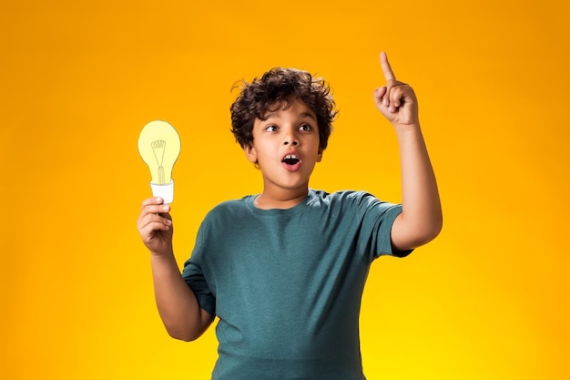 Foto Überraschendes kind, ein junge, der eine papierlampe hält und den finger nach oben hält erfolgsmotivation gewinner geniale idee konzept