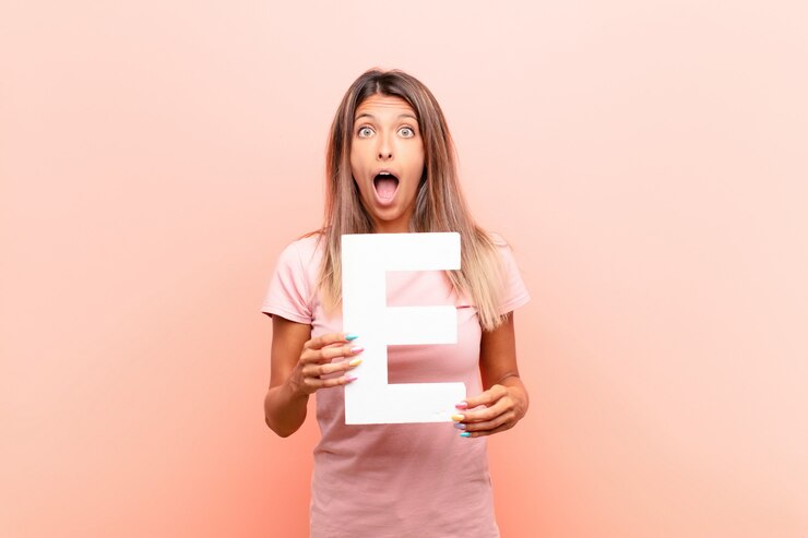 Foto überrascht, schockiert, erstaunt, den buchstaben e des alphabets haltend, um ein wort oder einen satz zu bilden.