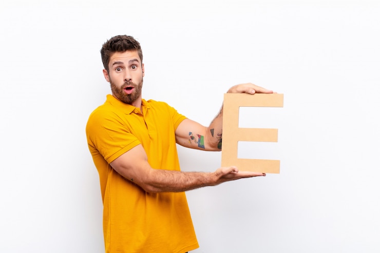 Foto überrascht, schockiert, erstaunt, den buchstaben e des alphabets haltend, um ein wort oder einen satz zu bilden.