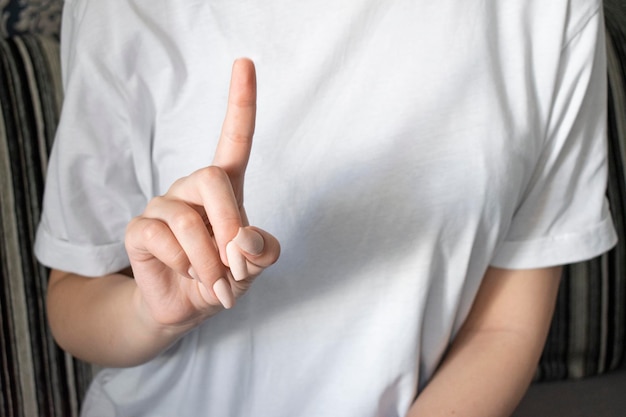 Foto Überraschte frau, die produkt zeigt. schönes mädchen mit dem lockigen haar, das einen finger auf die spitze zeigt.