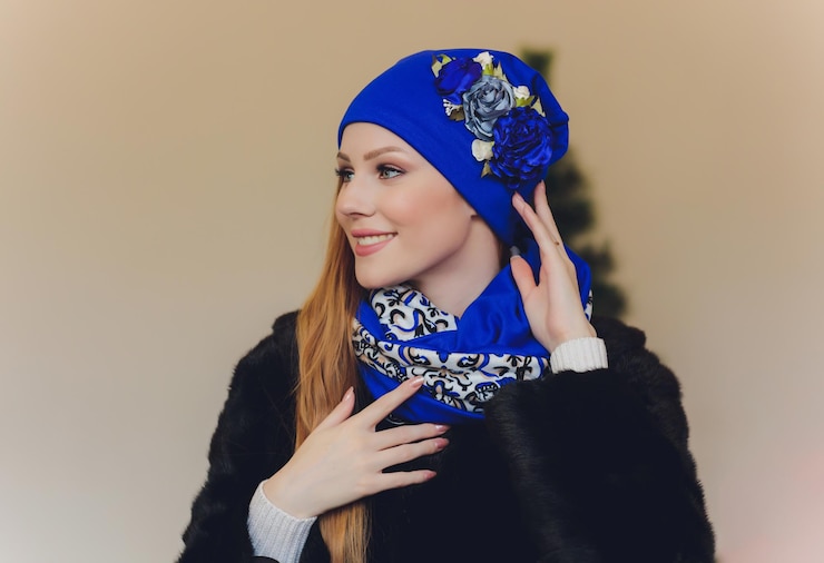 Foto überraschte, glückliche, schöne frau, die in aufregung seitwärts schaut. weihnachtsmädchen trägt einen gestrickten warmen hut und handschuhe, isoliert auf grauem hintergrund.