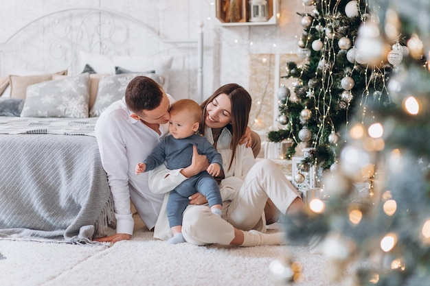 Überraschter Blick. Schöne Familie sitzt am Winterabend mit Geschenkboxen in der Nähe des Weihnachtsbaums