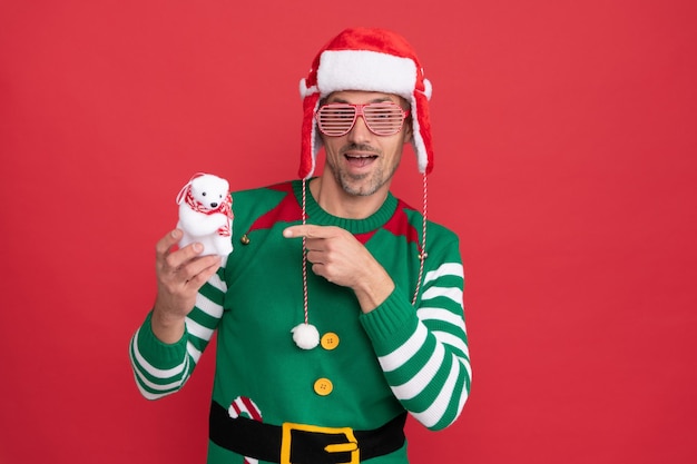 Foto Überraschter typ mit partybrille zeigt mit dem finger auf weihnachtsdekorations-schneemann