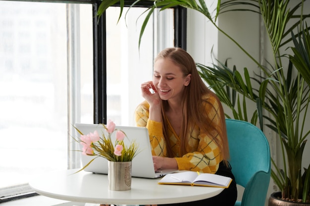 Foto Überzeugte junge frau in der intelligenten freizeitkleidung, die an laptop arbeitet