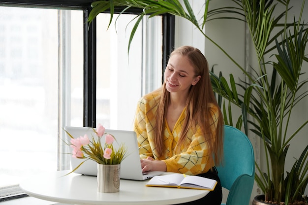 Foto Überzeugte junge frau in der intelligenten freizeitkleidung, die an laptop arbeitet