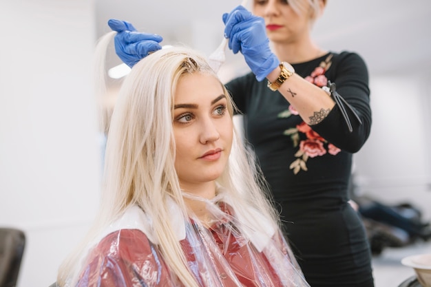 Foto Überzeugter friseur, der junges mädchen im wohnzimmer färbt