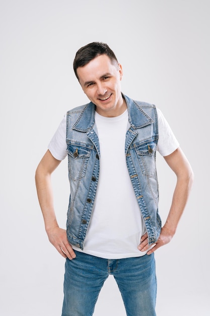 Ufa rússia 31 de março de 2020 bonito jovem confiante em roupas jeans olhando para a câmera em pé contra um fundo branco conceito de apostar emoções brilhantes por um ator profissional