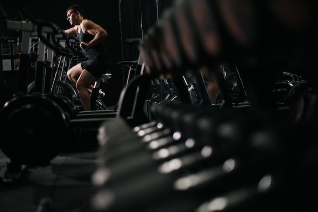 Ufa, rússia - 31 de outubro de 2019 homem musculoso forte se exercitando no simulador durante o treino esportivo no ginásio moderno conceito de estilo de vida saudável.