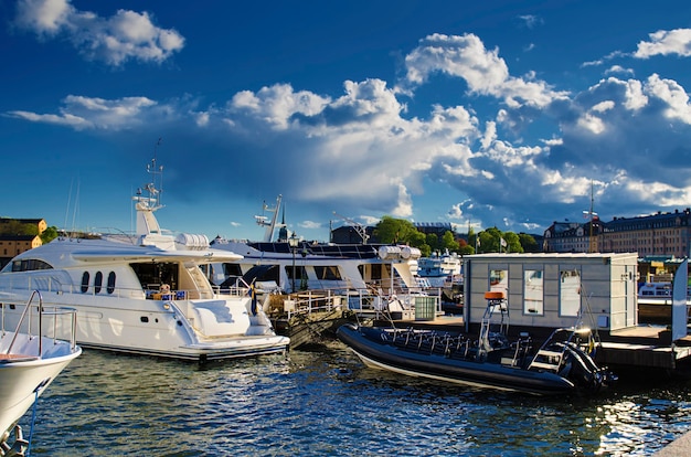 Ufer von Stockholm mit Yachten, Wasserreflexion, Schiffen und tiefblauem Himmel mit Wolken