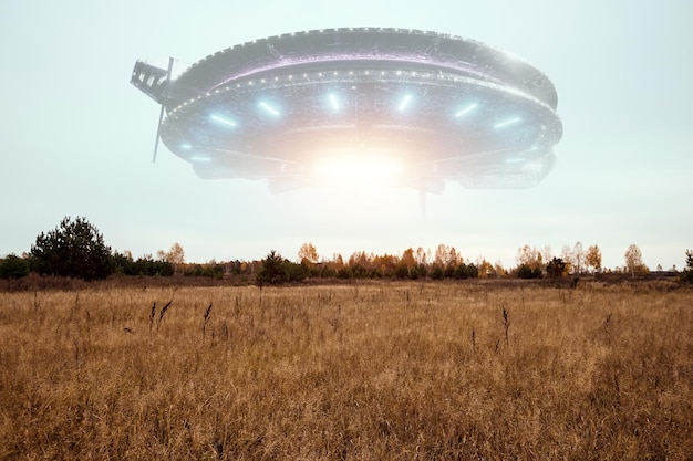 UFO eine außerirdische Untertasse, die über dem Feld in den Wolken schwebt, die bewegungslos am Himmel schwebt