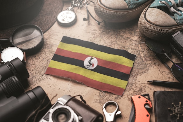 Uganda-Flagge zwischen dem Zubehör des Reisenden auf alter Weinlese-Karte. Touristisches Bestimmungsort-Konzept.