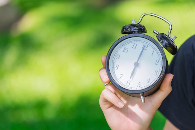 Foto uhr an hand, die zeit um 6 uhr auf grünem park zeigt