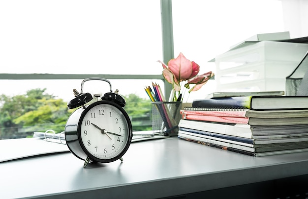 Uhr auf Schreibtischbüro mit stationärem im Sonnenlichtmorgen mit buntem