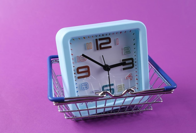 Uhr mit einem Warenkorb auf lila Hintergrund Einkaufszeit