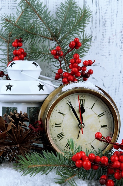 Uhr mit Tannenzweigen und Weihnachtsschmuck auf dem Tisch auf Holzuntergrund