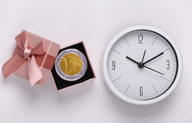 Uhr und Geschenkbox mit Münze auf weißem