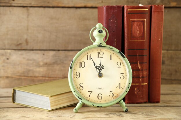 Uhr und Vintage-Bücher auf rustikalem Holzhintergrund