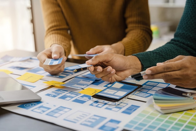 UI-Entwickler und UI-Designer beim Brainstorming über das Wireframe-Design der mobilen App-Schnittstelle mit Kundeninformationen und Farbcode im Büro