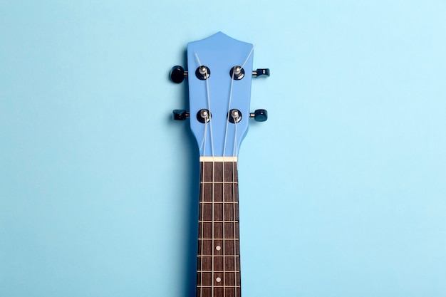 Ukelele de guitarra sobre un fondo azul. Concepto de música tocando la guitarra.