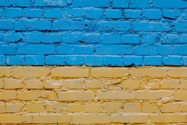 Ukraine Flagge gemalt auf alte Backsteinmauer, Hintergrund der gelb-blauen Backsteinmauer