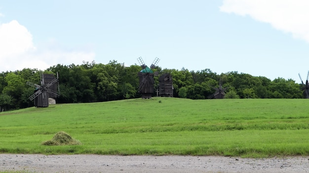 Ukraine, Kiew - 11. Juni 2020. Alte ukrainische Holzwindmühlen des 19. Jahrhunderts. Sommerlandschaft im Freien. Freilichtmuseum der Volksarchitektur und des Lebens, Pirogovo, Ukraine. Tourismus und Reisen.