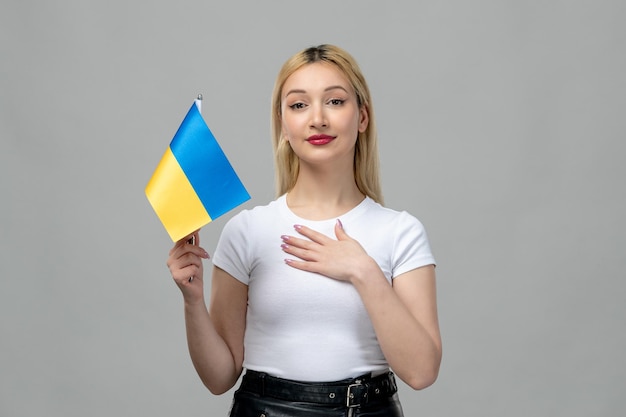 Ukraine russischer Konflikt blondes süßes Mädchen mit rotem Lippenstift und ukrainischer Flagge, die Brust hält