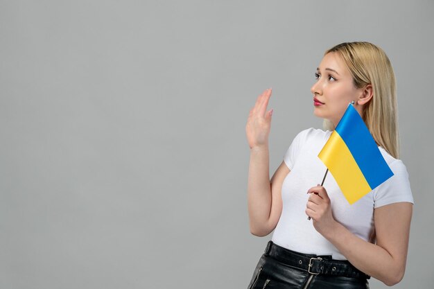 Ukraine russischer Konflikt blondes süßes Mädchen mit rotem Lippenstift und ukrainischer Flagge mit Stoppschild
