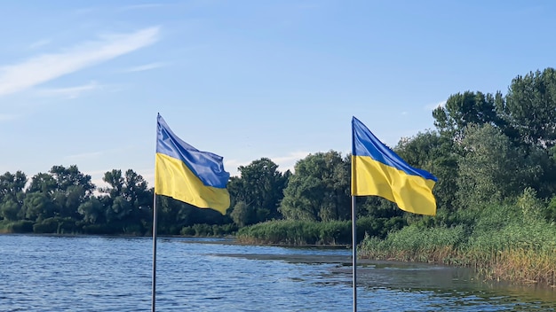 Ukrainische Fahnen flattern auf dem Pier des Flusses Sonniger Sommertag Symbole der Ukraine