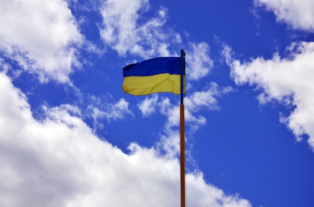 Ukrainische Flagge gegen den blauen Himmel mit Wolken