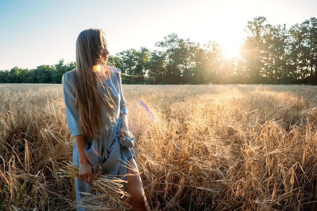 Ukrainische junge Frau, die während des sonnigen Tages Weizenernte auf dem Feld hält, gesichtsloses Porträt von