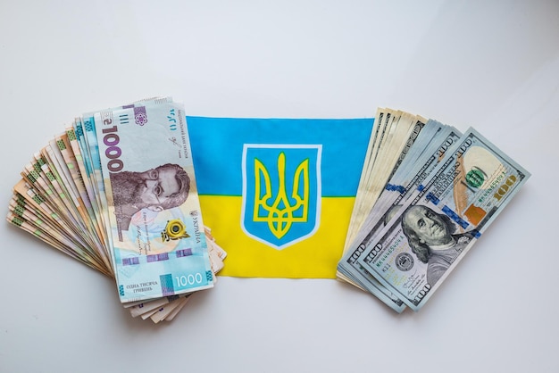 Ukrainische Währung Griwna und US-Dollar vor dem Hintergrund der ukrainischen Flagge Staatliche Hilfe für Bürger im Zusammenhang mit dem Krieg in der Ukraine