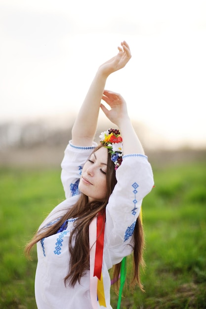 Ukrainisches Mädchen in einem Hemd und einem Blumenkranz auf dem Kopf, der Ihre Hände hochzieht